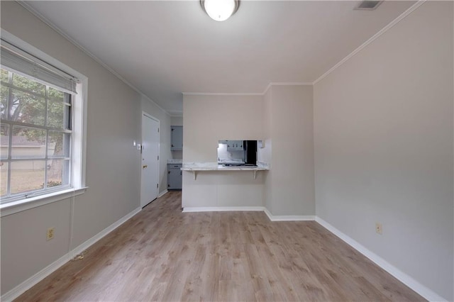 unfurnished living room with a wealth of natural light, light hardwood / wood-style floors, and ornamental molding