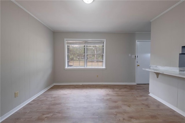 spare room featuring ornamental molding and light hardwood / wood-style flooring