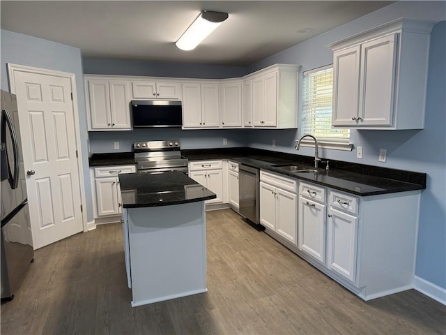 kitchen with white cabinets, appliances with stainless steel finishes, a kitchen island, and sink