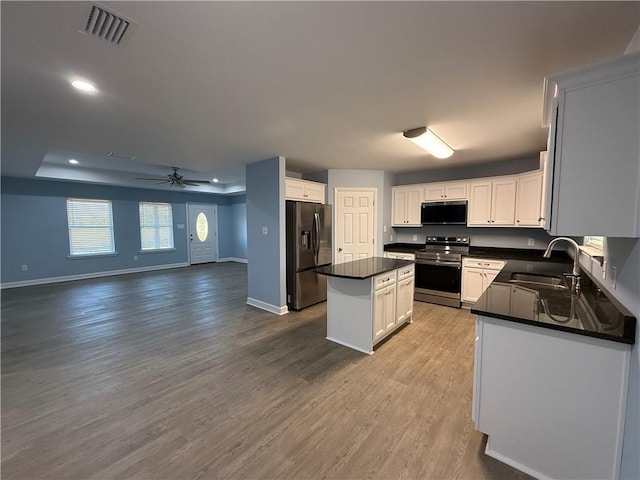 kitchen featuring appliances with stainless steel finishes, a center island, white cabinetry, and sink