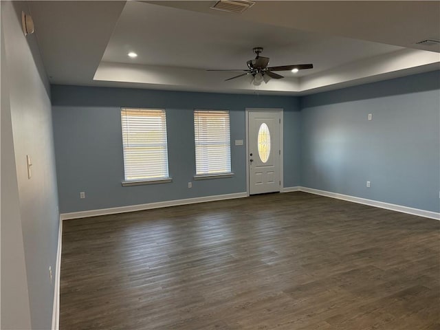 foyer entrance with ceiling fan, a raised ceiling, and dark wood-type flooring