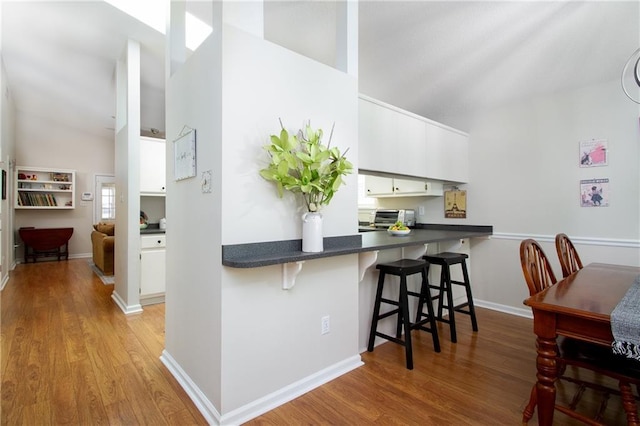 1000 Pinemont Dr, Mobile, AL 36609 - kitchen with a kitchen breakfast bar, light wood-style floors, white cabinets, dark countertops, and vaulted ceiling