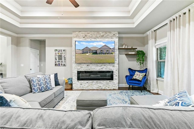 living room with a raised ceiling, a fireplace, wood-type flooring, and ornamental molding