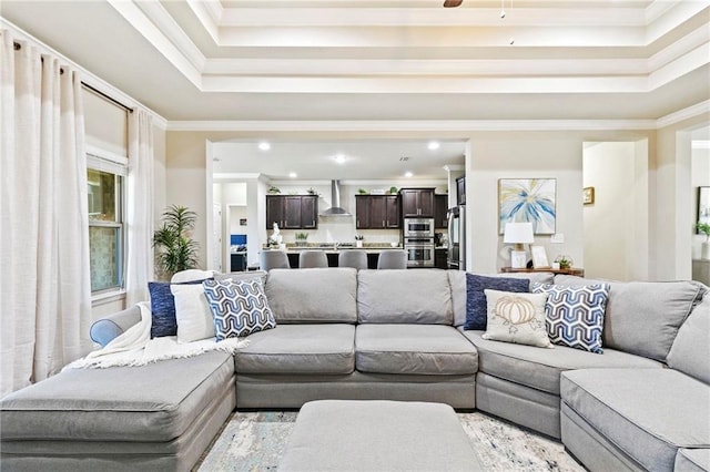 living room featuring a tray ceiling, ceiling fan, and ornamental molding