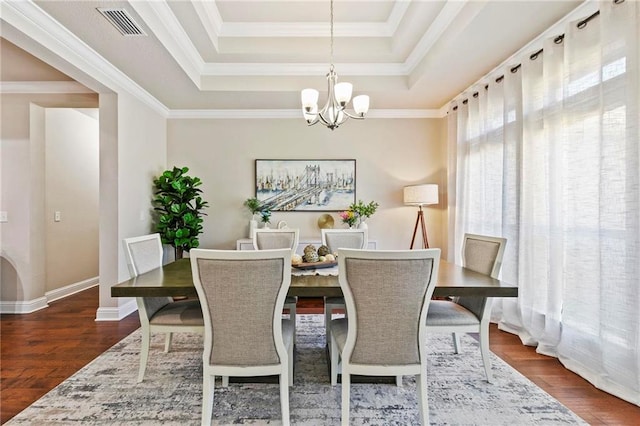 dining room featuring dark hardwood / wood-style floors, a raised ceiling, ornamental molding, and a chandelier