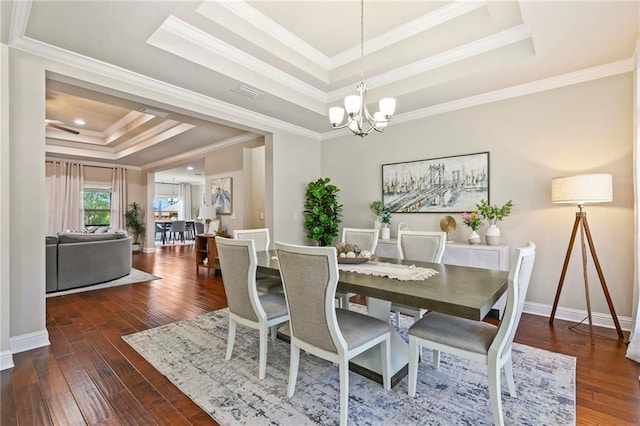 dining area featuring dark hardwood / wood-style floors, ornamental molding, a chandelier, and a tray ceiling