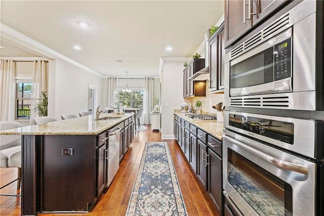 kitchen with a breakfast bar, a wealth of natural light, a center island with sink, and appliances with stainless steel finishes