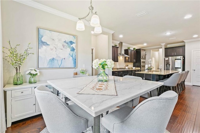 dining area with sink, dark hardwood / wood-style flooring, crown molding, and a notable chandelier