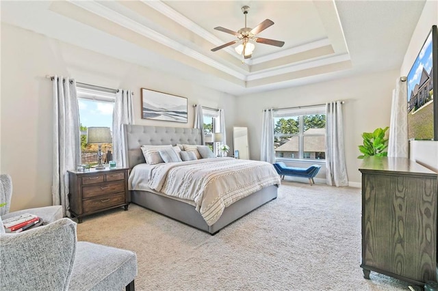 bedroom with a raised ceiling, ceiling fan, and light colored carpet