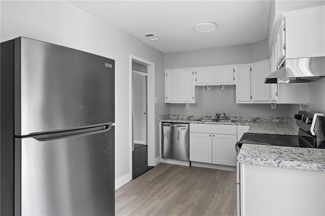 kitchen with sink, stainless steel appliances, light stone counters, white cabinets, and light wood-type flooring