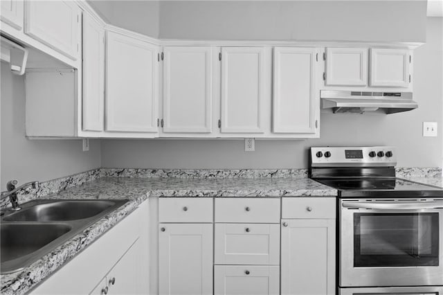 kitchen featuring white cabinetry, light stone counters, sink, and stainless steel range with electric cooktop