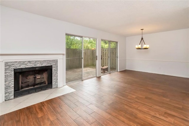 unfurnished living room featuring a notable chandelier, a fireplace, and light hardwood / wood-style floors