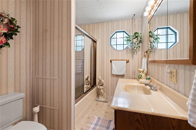 full bathroom featuring combined bath / shower with glass door, plenty of natural light, vanity, and toilet