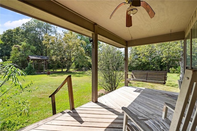 wooden deck featuring a lawn, ceiling fan, and a gazebo