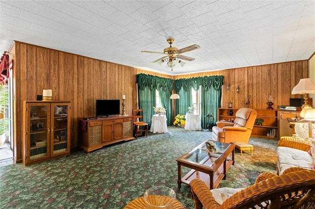 living room with ceiling fan, wooden walls, and carpet