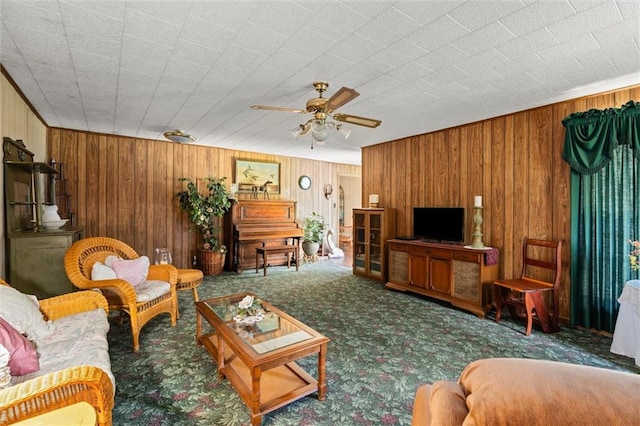 living room with ceiling fan, carpet floors, and wooden walls