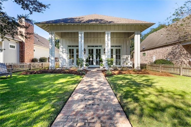 exterior space featuring board and batten siding, french doors, fence, and a lawn