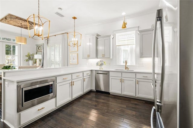 kitchen featuring a peninsula, a sink, visible vents, appliances with stainless steel finishes, and dark wood finished floors