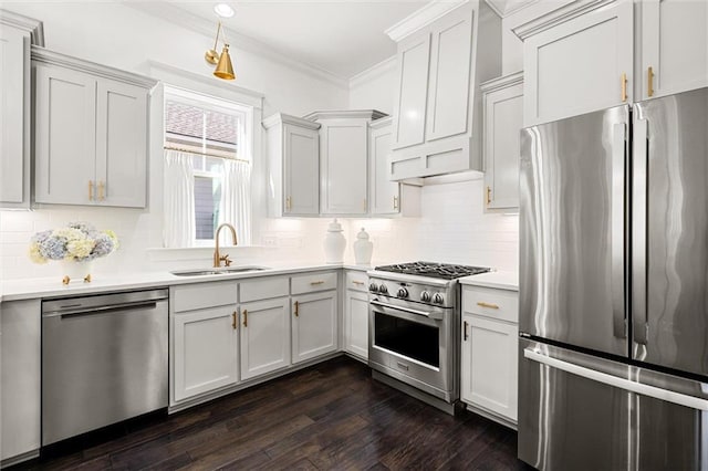 kitchen with dark wood-style flooring, light countertops, appliances with stainless steel finishes, ornamental molding, and a sink