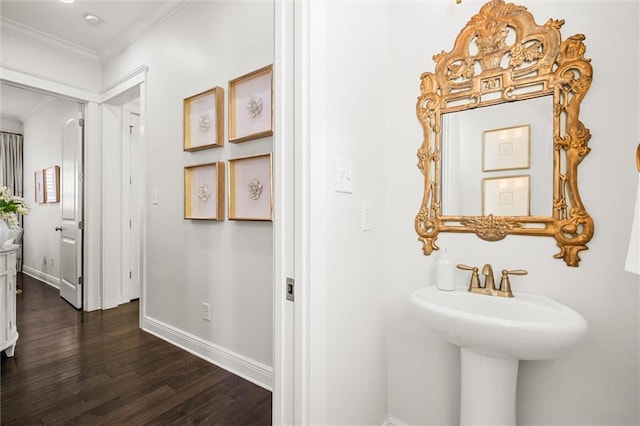 bathroom with a sink, crown molding, baseboards, and wood finished floors