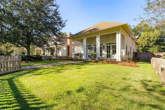 rear view of property featuring a lawn and fence