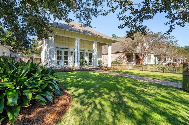 rear view of property featuring a yard, board and batten siding, and fence