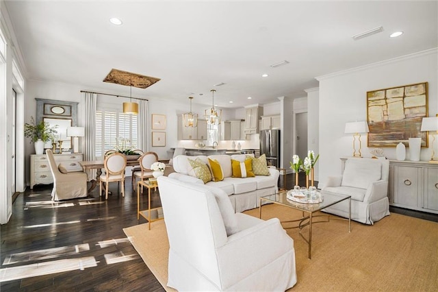 living area with recessed lighting, visible vents, crown molding, and wood finished floors