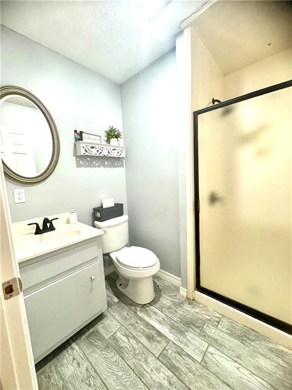 bathroom featuring vanity, toilet, and a shower with shower door