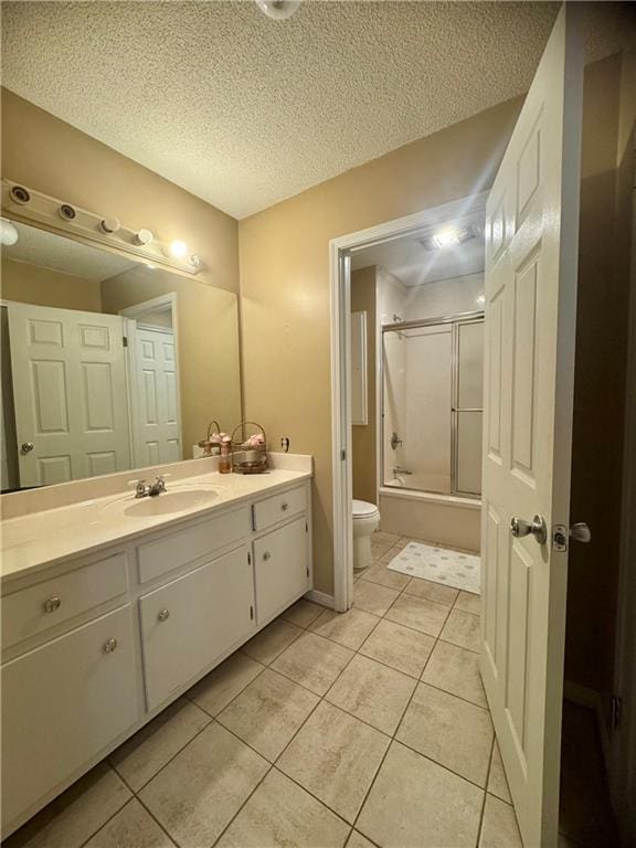 full bathroom featuring enclosed tub / shower combo, vanity, a textured ceiling, tile patterned floors, and toilet