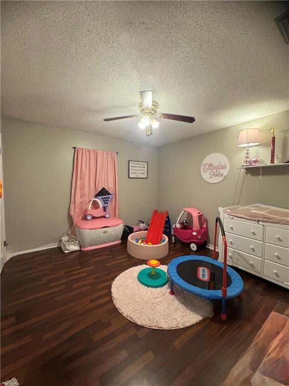 recreation room with ceiling fan, dark hardwood / wood-style floors, and a textured ceiling