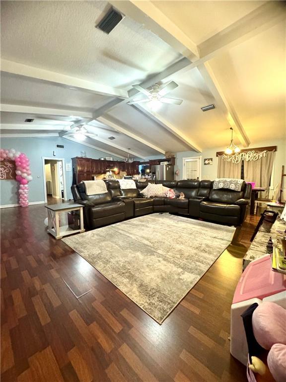 living room featuring vaulted ceiling with beams, ceiling fan with notable chandelier, a textured ceiling, and dark hardwood / wood-style floors