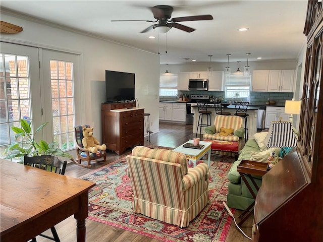 living room with hardwood / wood-style flooring, crown molding, and ceiling fan