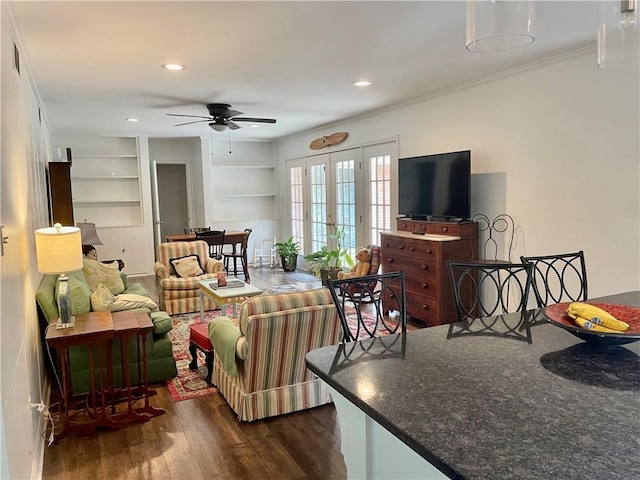 living room with ceiling fan, built in shelves, ornamental molding, french doors, and dark wood-type flooring