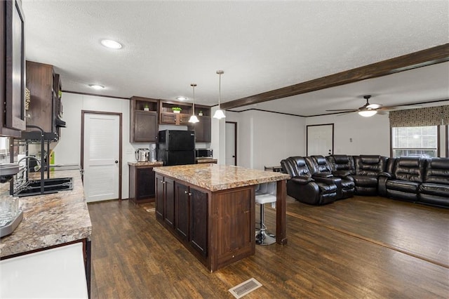 8801 Jack Williams Rd, Wilmer, AL 36587 - kitchen with freestanding refrigerator, dark brown cabinetry, dark wood-type flooring, ceiling fan, and a kitchen breakfast bar