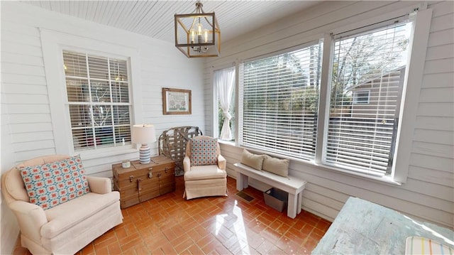 sitting room with brick floor, visible vents, an inviting chandelier, and wood walls