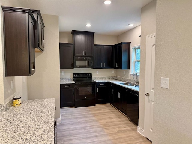 kitchen featuring light hardwood / wood-style flooring, light stone countertops, black appliances, and sink