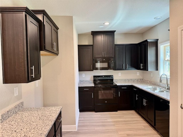 kitchen with light stone countertops, baseboards, light wood finished floors, a sink, and black appliances