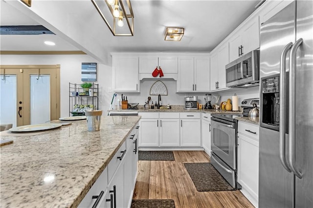 kitchen with appliances with stainless steel finishes, light hardwood / wood-style floors, white cabinetry, sink, and ornamental molding