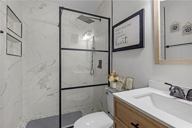 bathroom with toilet, a tile shower, and vanity