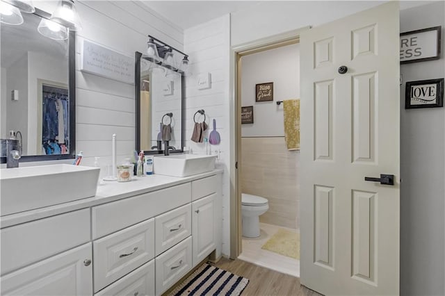 bathroom with vanity, toilet, tile walls, and wood-type flooring