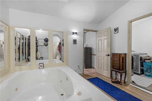 bathroom featuring a tub to relax in, hardwood / wood-style flooring, and washer / clothes dryer