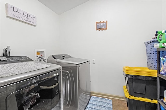 clothes washing area featuring washer and clothes dryer and tile patterned floors