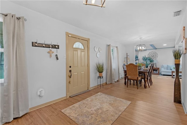 entryway with an inviting chandelier and light wood-type flooring