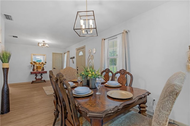 dining area with a notable chandelier and light hardwood / wood-style floors