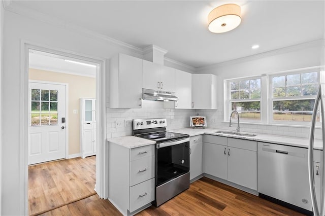 4630 General Rd, Mobile, AL 36619 - kitchen featuring appliances with stainless steel finishes, under cabinet range hood, decorative backsplash, ornamental molding, and dark wood finished floors