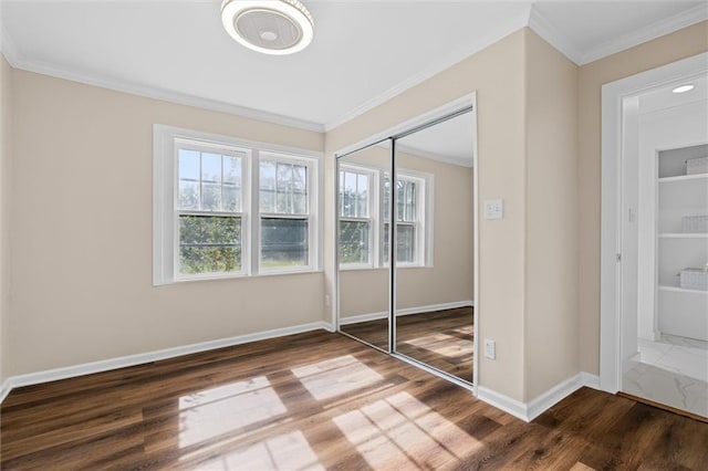 unfurnished bedroom with crown molding, a closet, and wood-type flooring