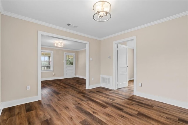 empty room featuring dark hardwood / wood-style floors, ornamental molding, and an inviting chandelier