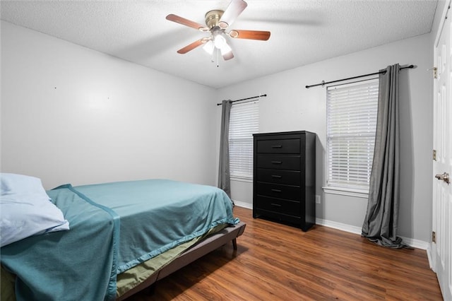 bedroom featuring a textured ceiling, ceiling fan, and dark wood-type flooring