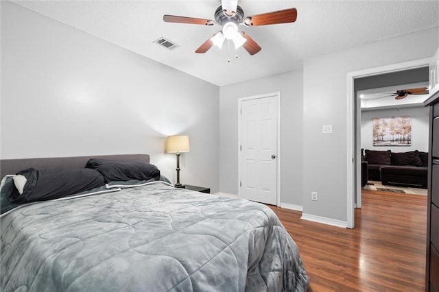 bedroom featuring ceiling fan, dark hardwood / wood-style flooring, and a textured ceiling