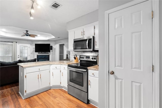 kitchen featuring kitchen peninsula, appliances with stainless steel finishes, ceiling fan, white cabinets, and light hardwood / wood-style floors